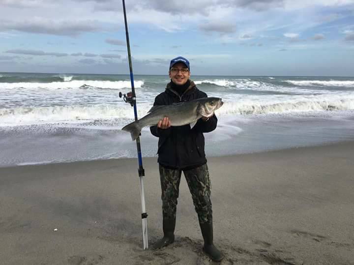Pescatore con spigola catturata a surfcasting