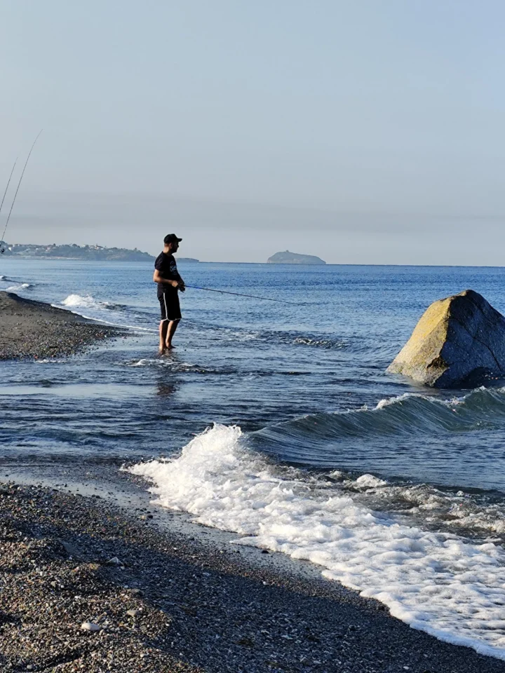 Pescatore in spinning sulla riva della foce del Lao a Scalea